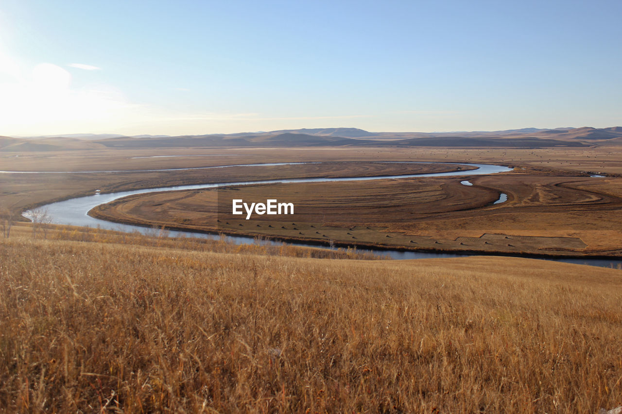 The quiet winding river is flanked by beautiful yellow prairie