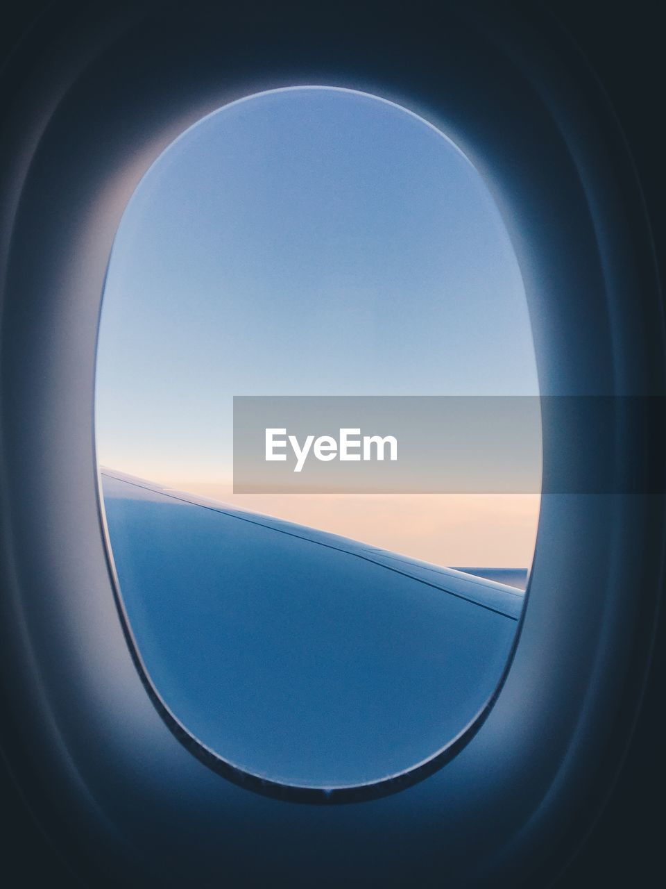 AIRPLANE WINDOW AGAINST CLEAR BLUE SKY SEEN THROUGH GLASS