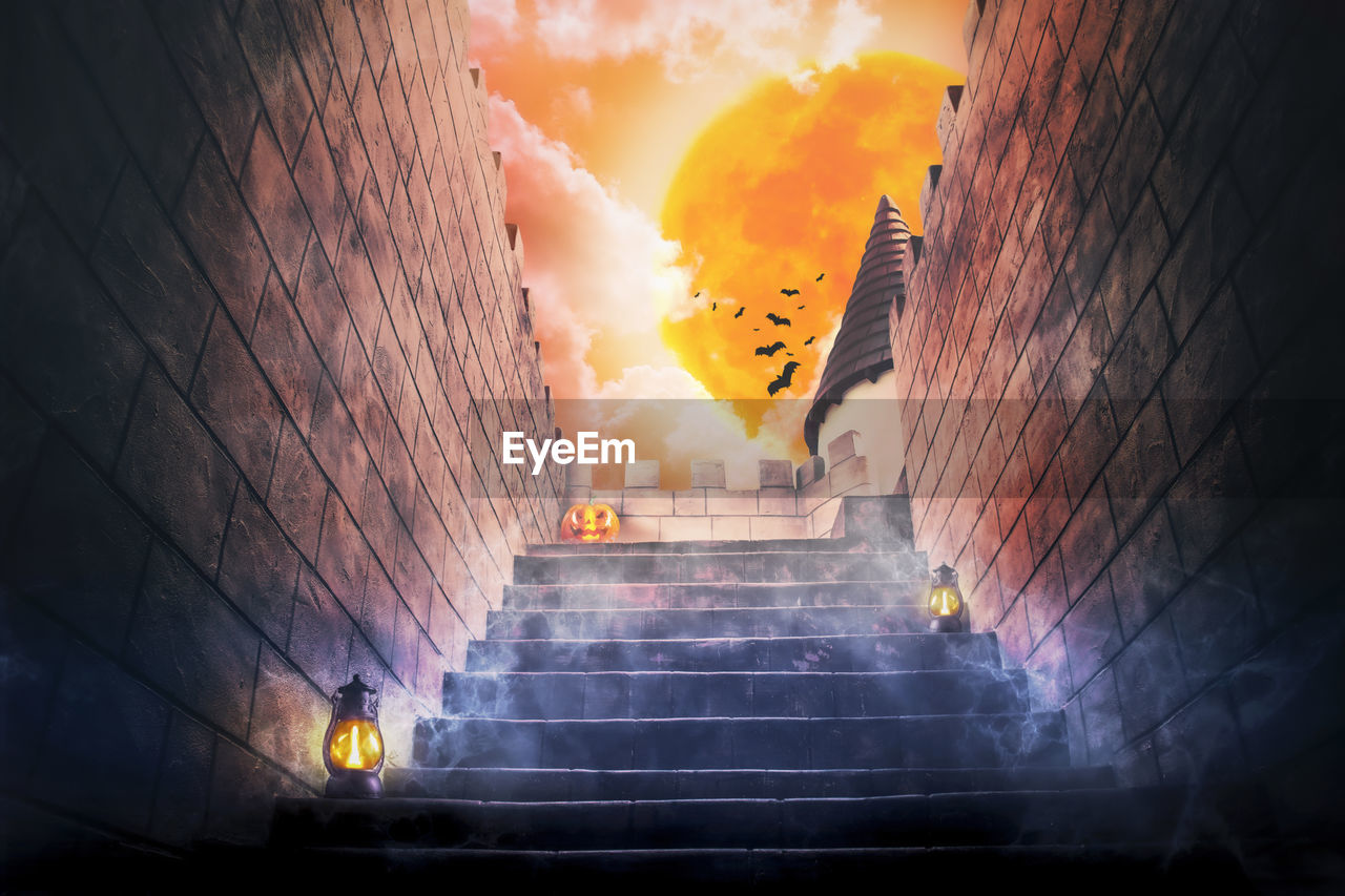 LOW ANGLE VIEW OF STAIRCASE AGAINST BUILDING DURING SUNSET