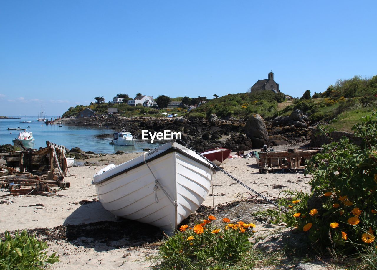 Boat moored at beach against clear blue sky