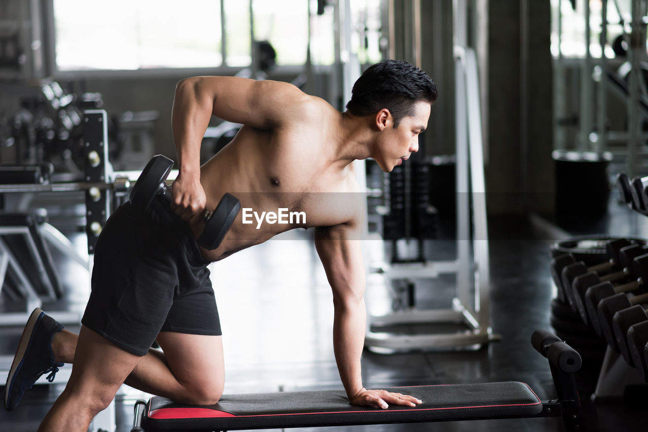 Young shirtless man exercising in gym