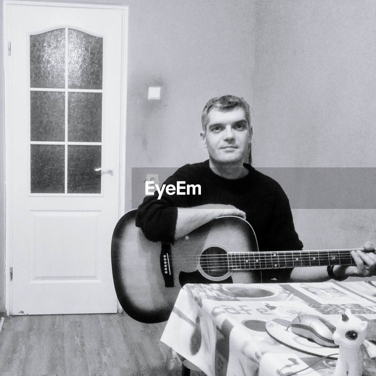 PORTRAIT OF A MAN PLAYING GUITAR AT HOME