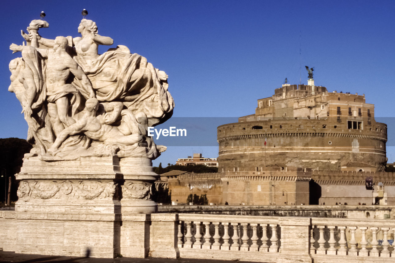 Imposing marble sculpture on bridge over tiber river and saint angelo castle in rome, italy.