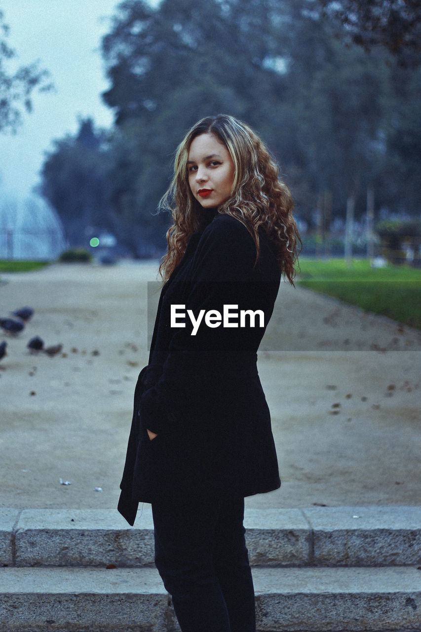 Portrait of young woman standing at park