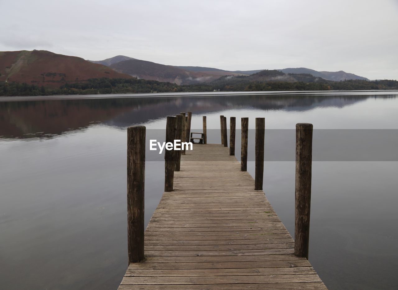 Wooden pier over lake against sky