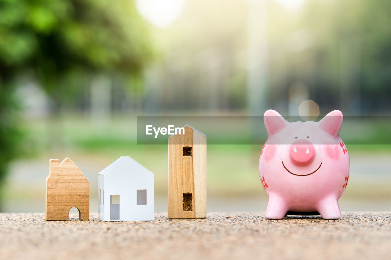 Close-up of piggy bank with model house outdoors