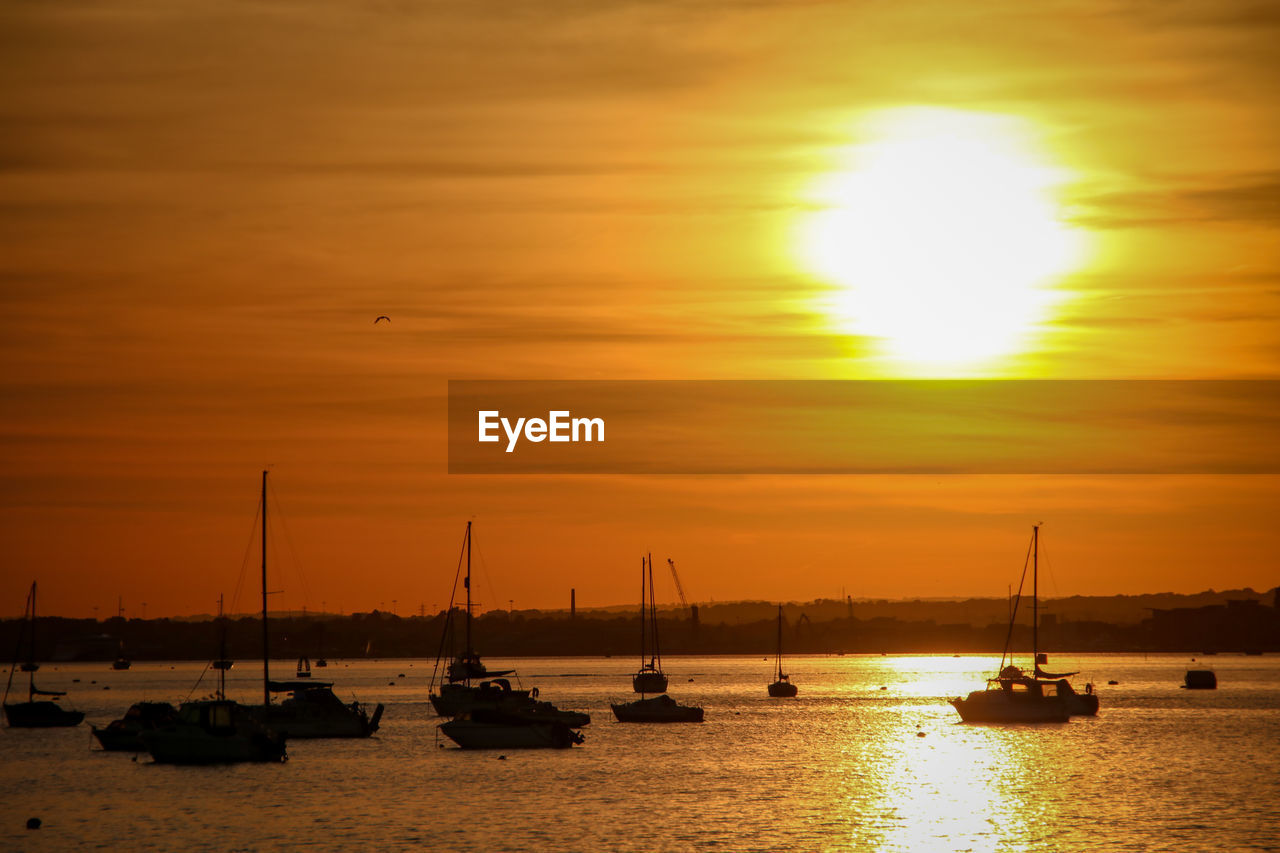 SILHOUETTE SAILBOATS ON SEA AGAINST ORANGE SKY