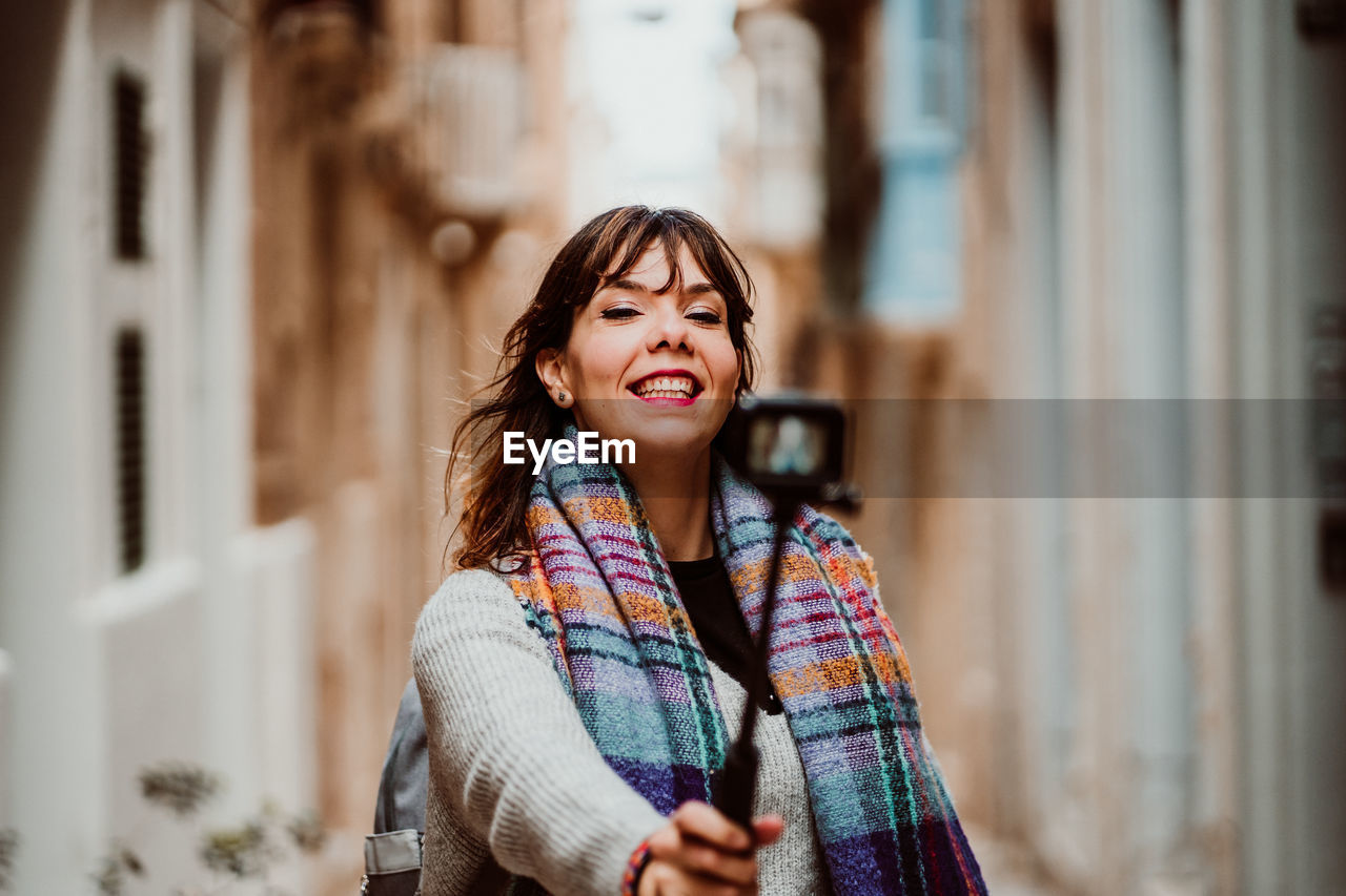 Woman holding monopod standing in alley