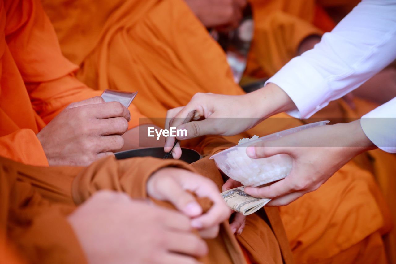 Cropped hands of person performing rituals with monks