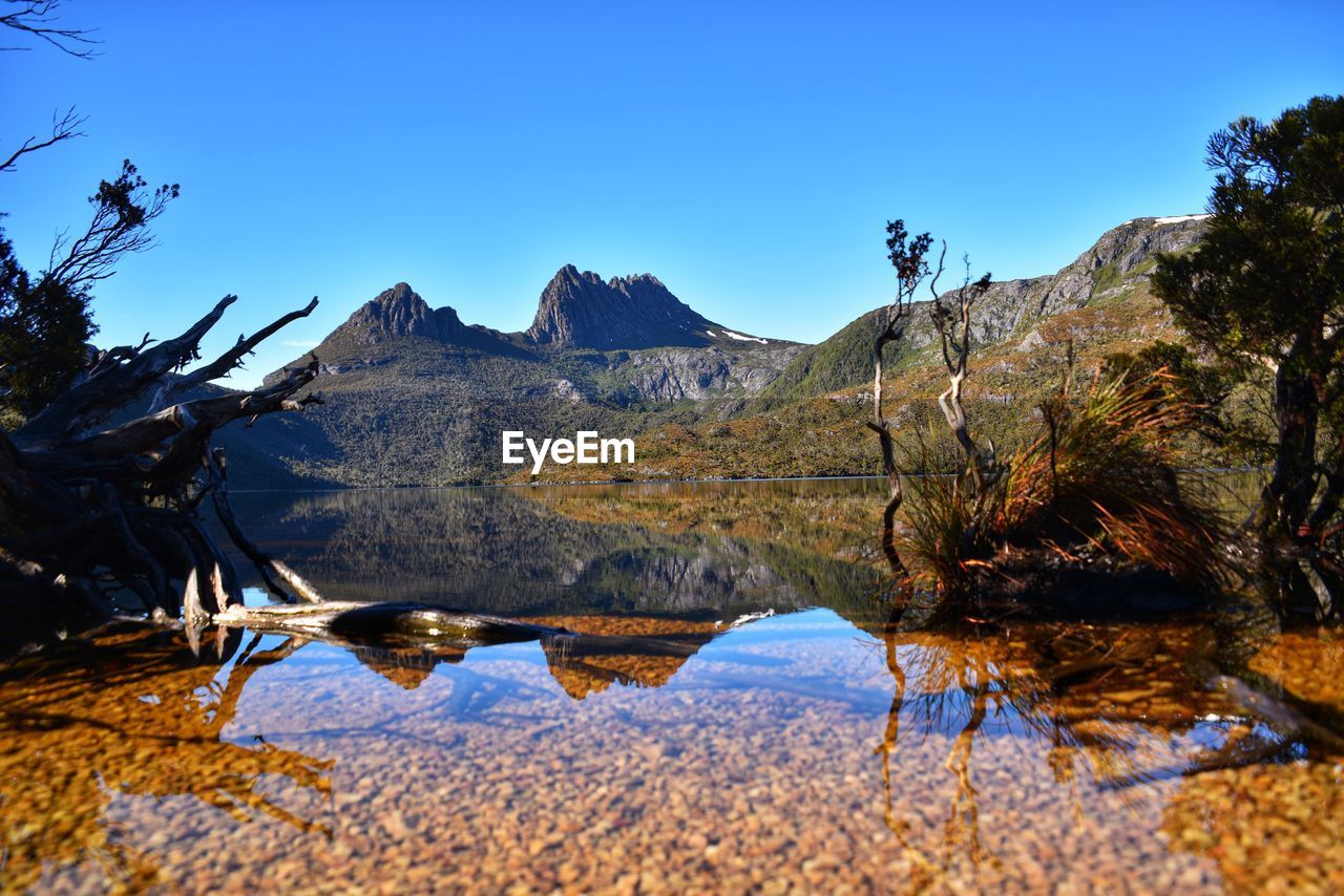 Scenic view of lake and mountains against clear blue sky