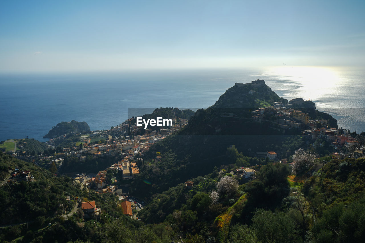 sky, horizon, sea, hill, land, scenics - nature, nature, coast, architecture, water, beauty in nature, environment, landscape, tree, building exterior, horizon over water, plant, city, building, built structure, travel destinations, outdoors, tranquility, travel, beach, no people, high angle view, cliff, aerial photography, cityscape, mountain range, cloud, blue, tourism, tranquil scene, terrain, dusk, sunlight, day, coastline, ocean, urban skyline, residential district