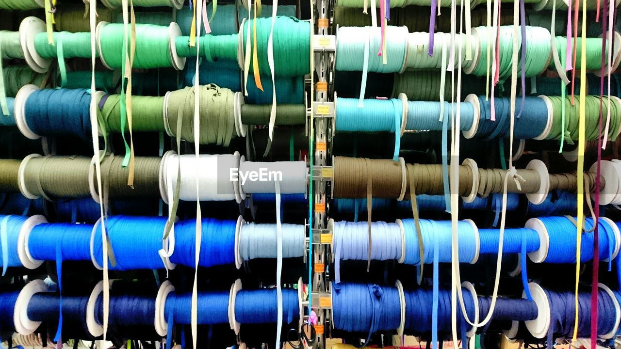 Full length of multi colored spools in workshop