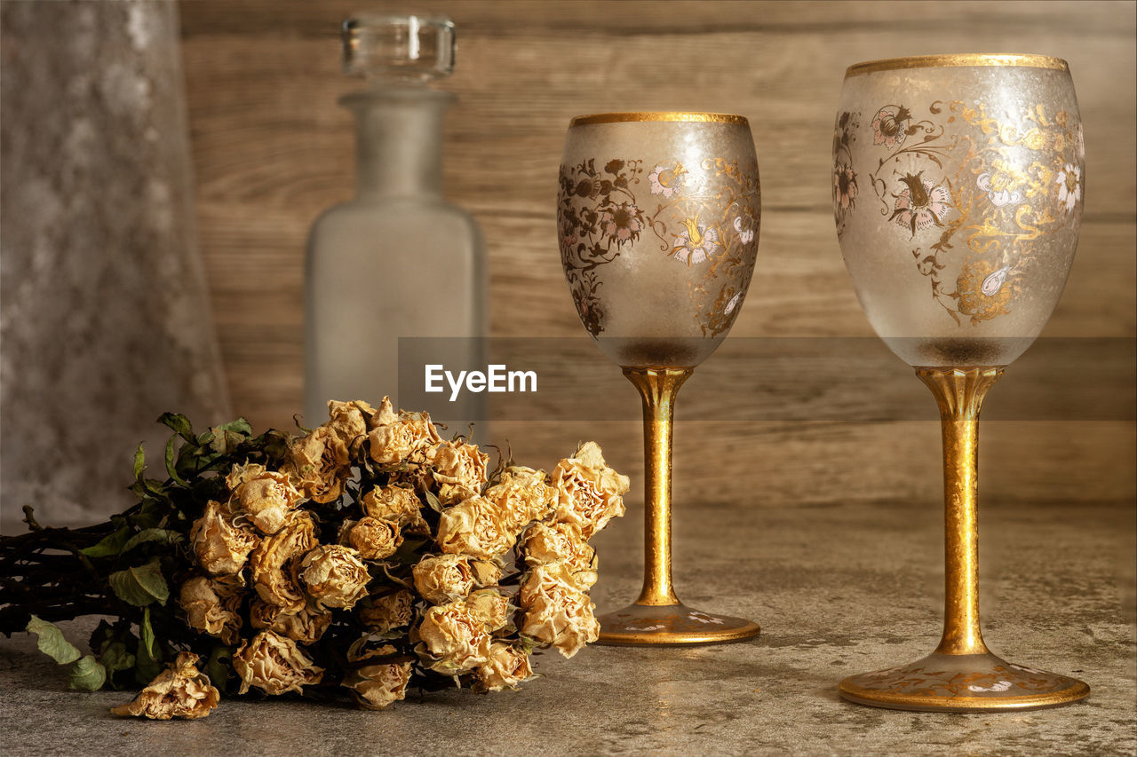 Still life of two empty glass of wine with wine bottle and dry flowers bouquet