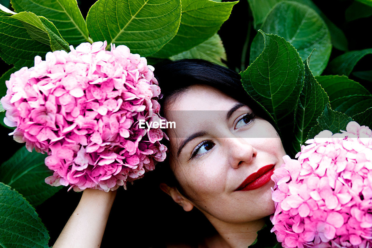 CLOSE-UP PORTRAIT OF BEAUTIFUL WOMAN WITH PINK FLOWER