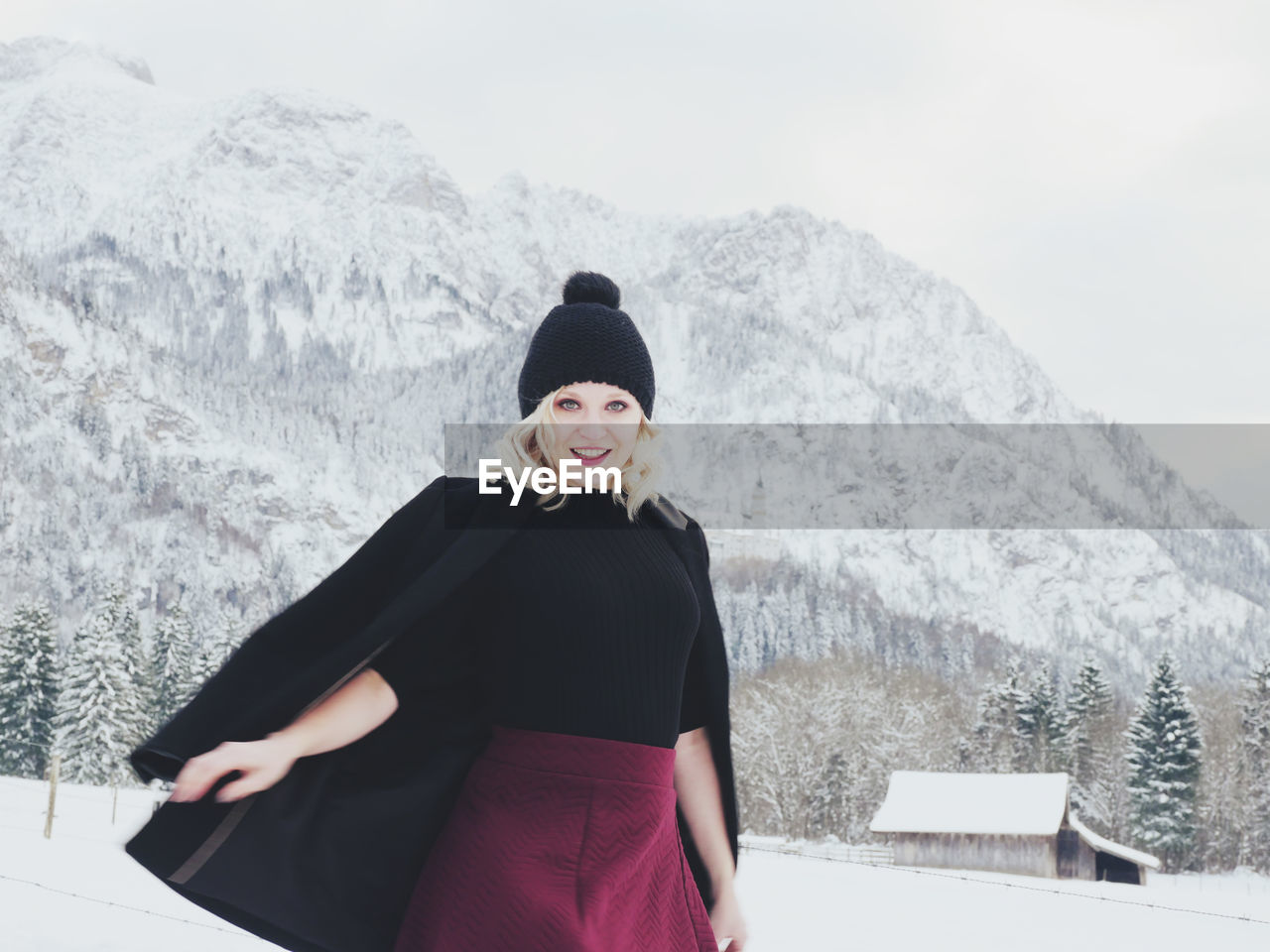 Portrait of mid adult woman standing on snow covered mountain against sky