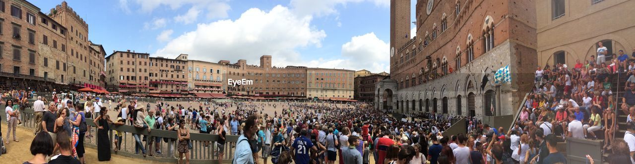 PANORAMIC VIEW OF PEOPLE ON STREET AGAINST SKY