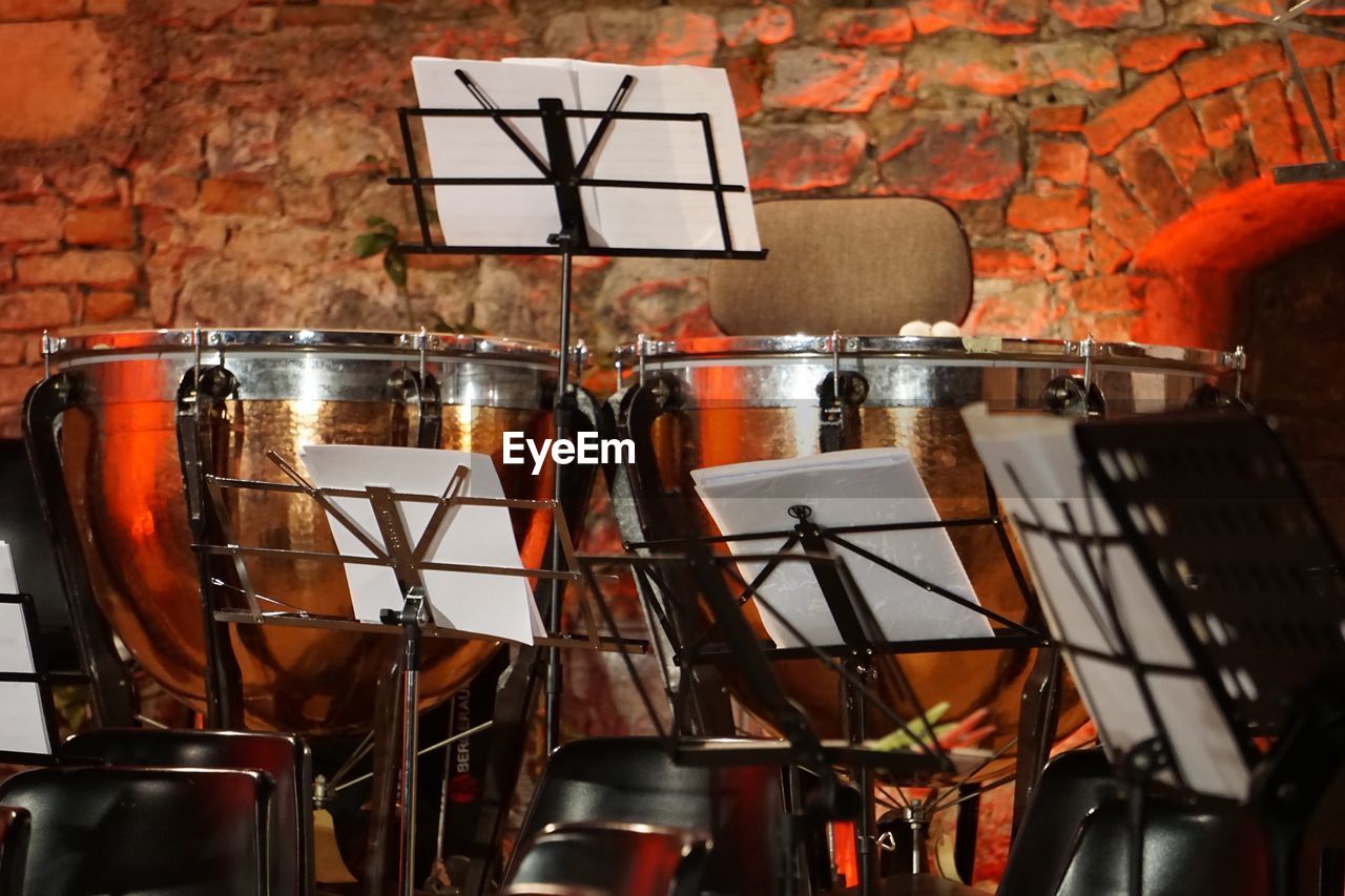 Close-up of drums and music sheets against brick wall