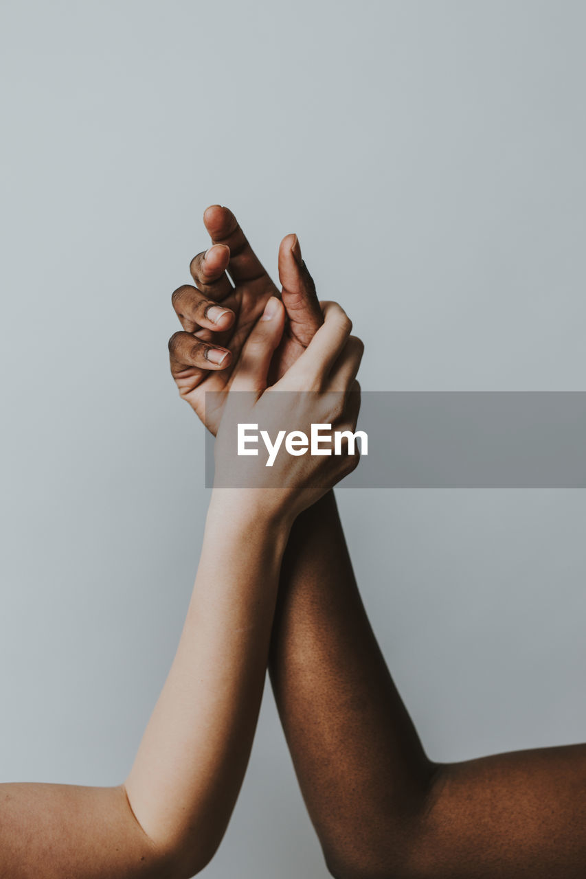 Cropped hands of women against gray background