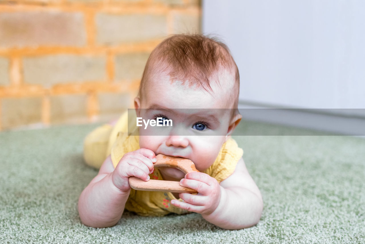 Little caucasian baby girl with wooden teething toy. eco-friendly toys for kids.