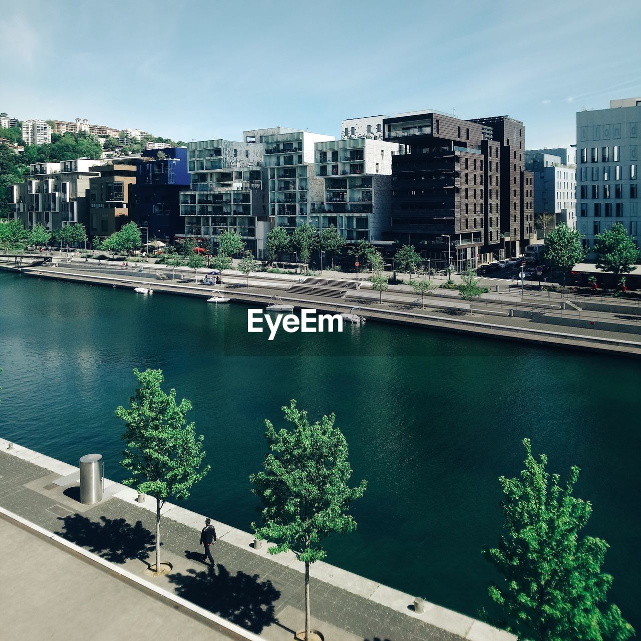 HIGH ANGLE VIEW OF SWIMMING POOL BY RIVER AGAINST BUILDINGS