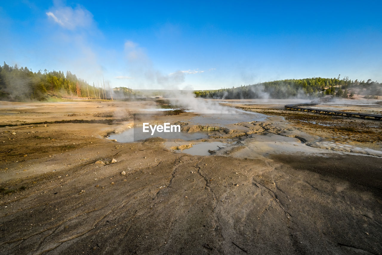 landscape, environment, sky, nature, body of water, geology, land, scenics - nature, water, steam, travel, travel destinations, beauty in nature, wave, hot spring, geyser, heat, morning, sea, cloud, blue, tourism, power in nature, volcano, shore, physical geography, smoke, mountain, no people, wilderness, non-urban scene, coast, outdoors, natural environment, volcanic landscape, day, accidents and disasters, social issues, sand, tree, fog, plant