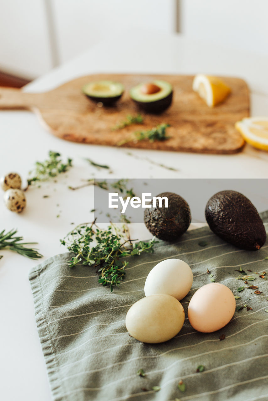 Ingredients for a meal: avocado, eggs, aromatic herbs on a table