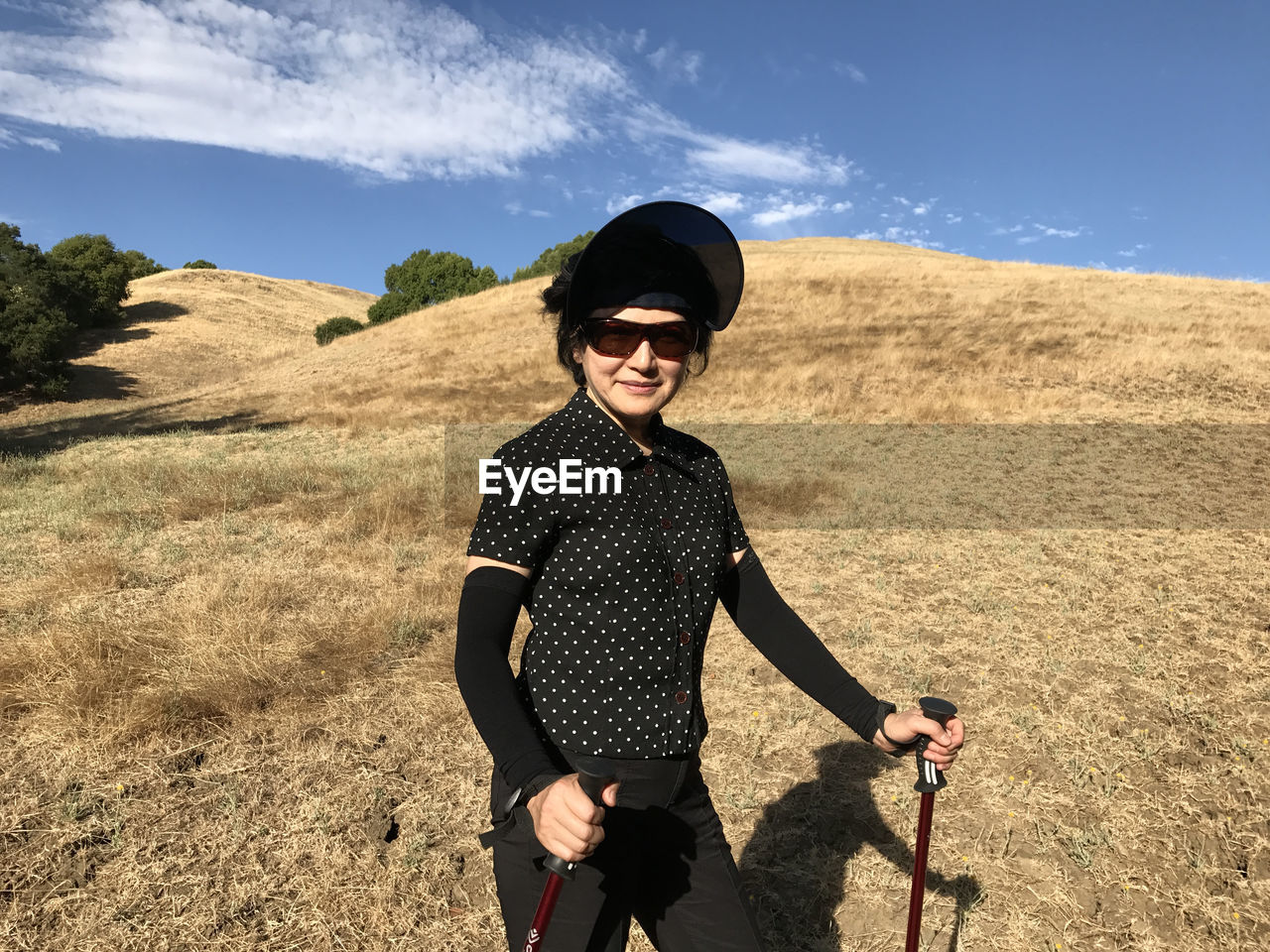 Portrait of young woman wearing sunglasses standing on grassy field at garin regional park