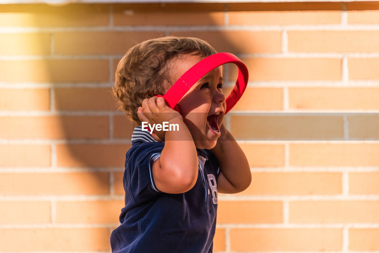 Portrait child listening to music with headphones on brick wall