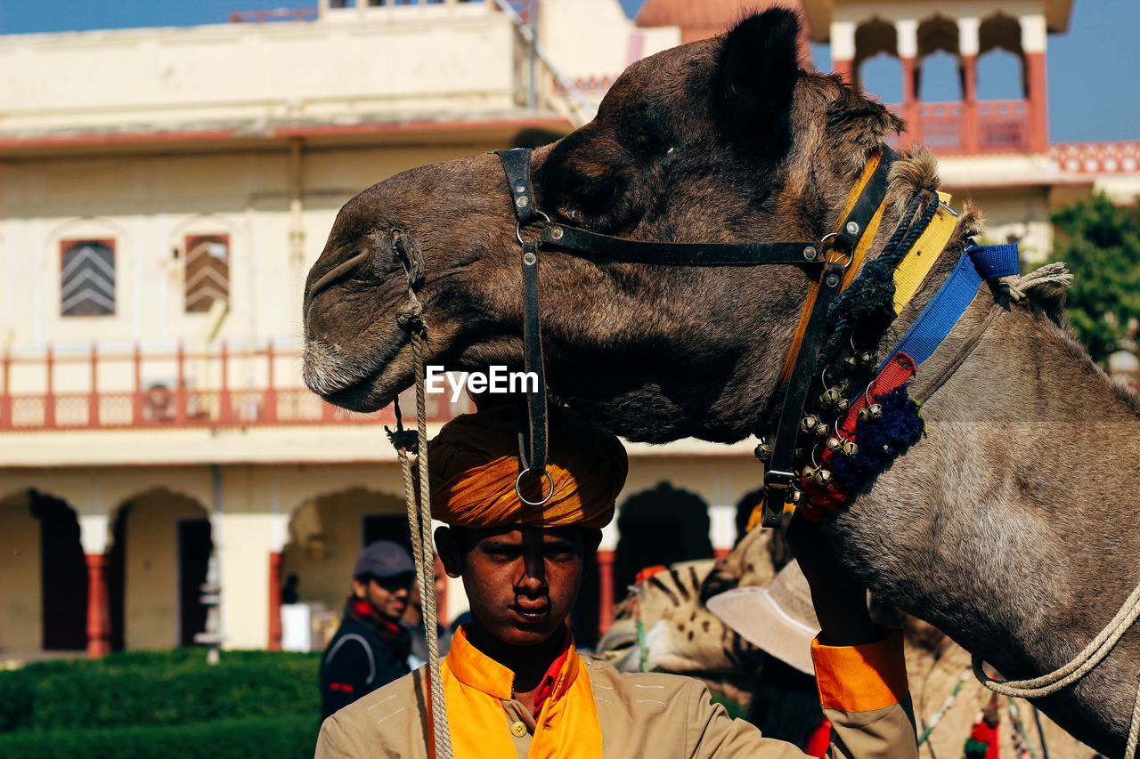 Portrait of man by camel against building