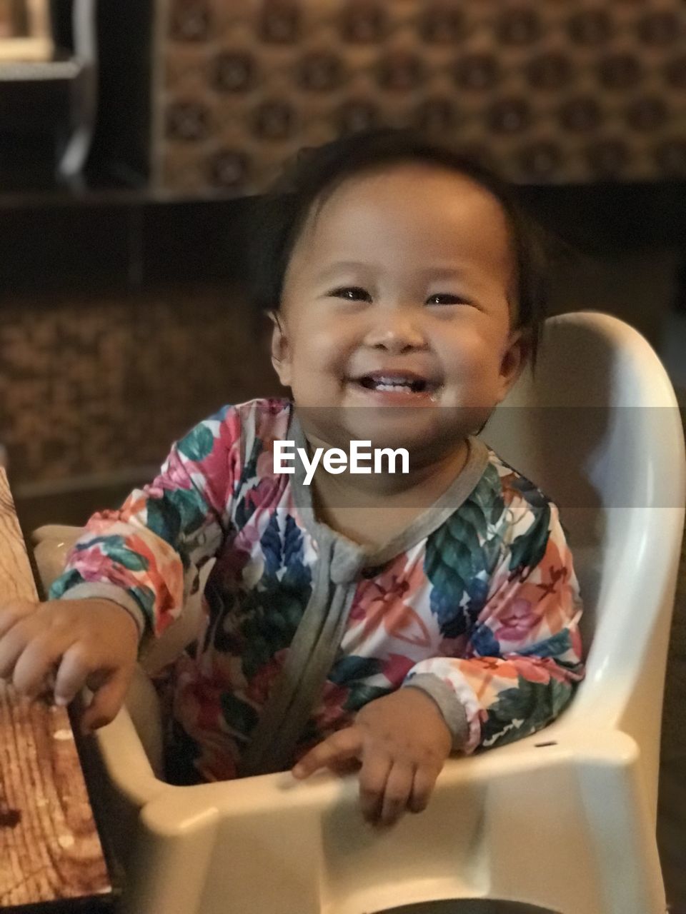 PORTRAIT OF CUTE BABY GIRL SITTING AT HOME