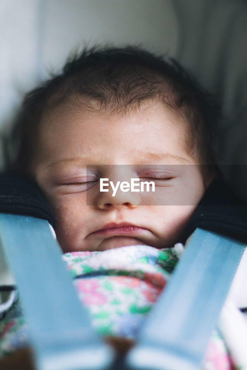 Close-up of cute baby girl sleeping on baby stroller 