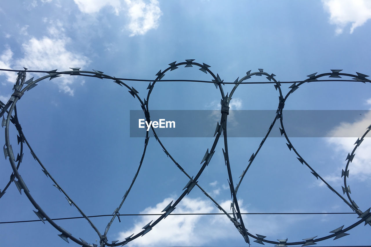 Low angle view of barbed wire against sky