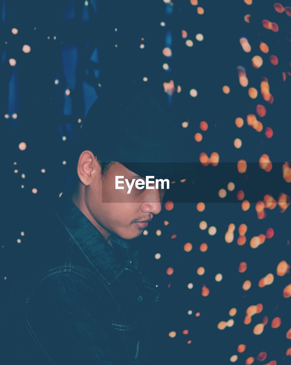 Man looking down against illuminated lights at night