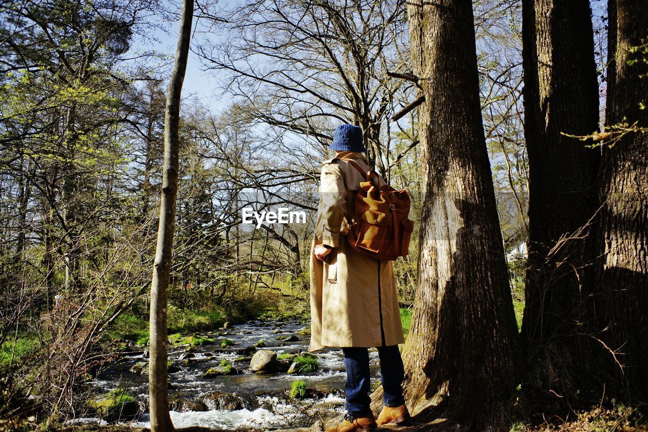 rear view of woman standing on tree trunk