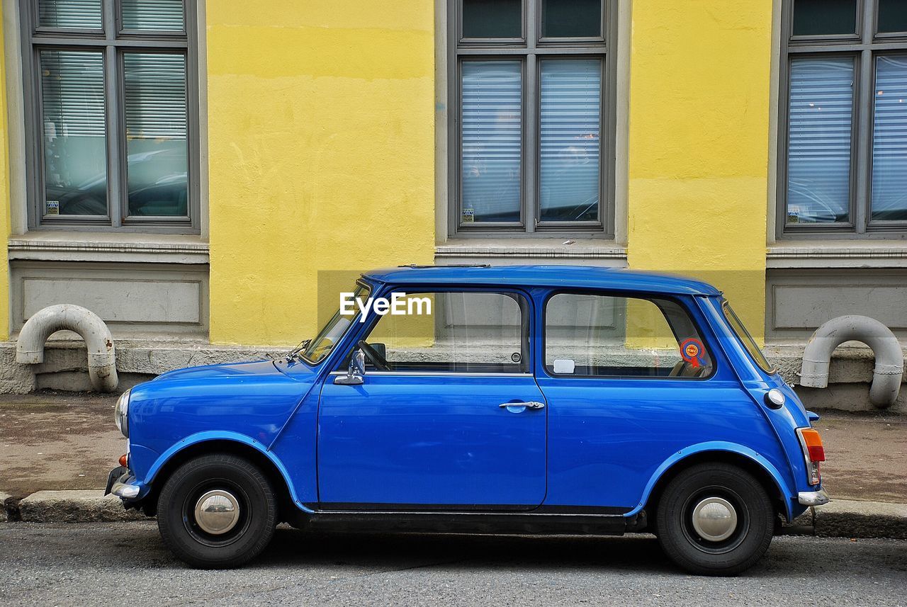 Blue car parked on roadside against building