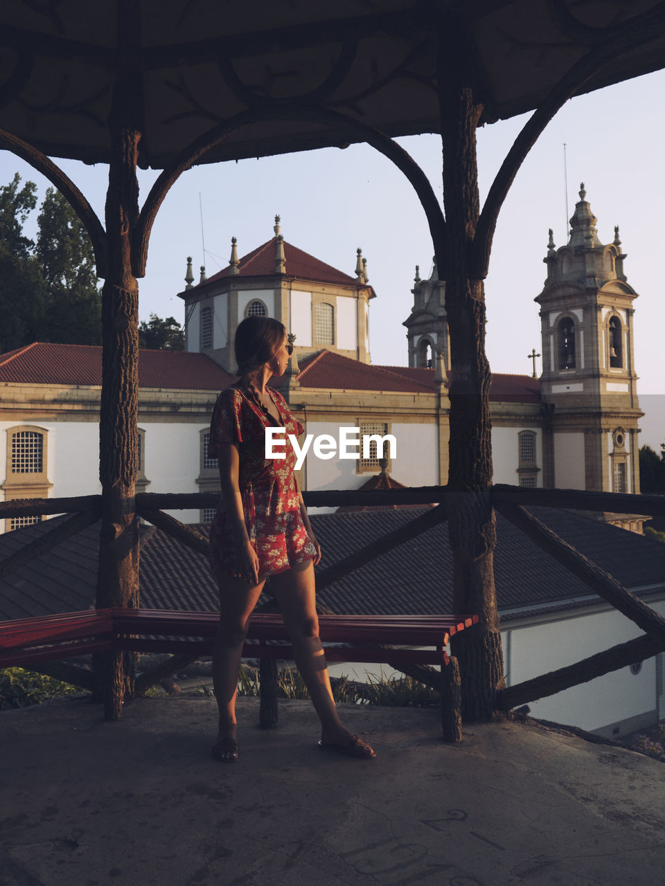 WOMAN STANDING ON RAILING AGAINST BUILDING