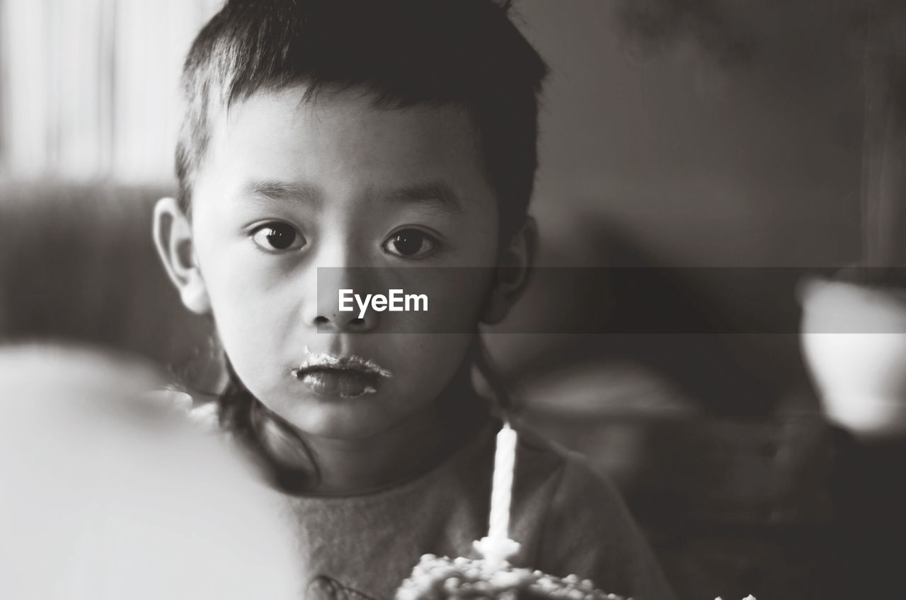 Portrait of boy with cake on face at home