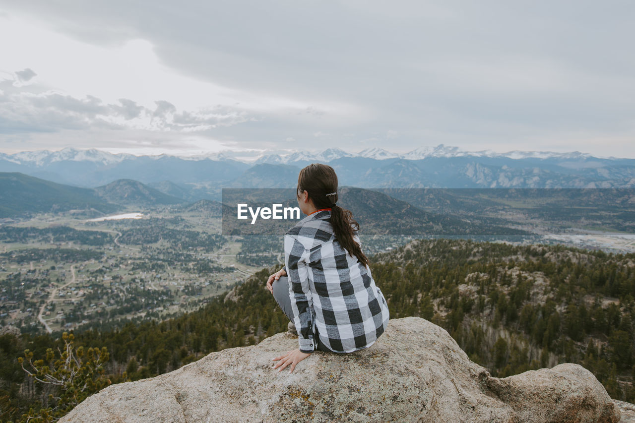 Rear view of woman looking at mountains against sky