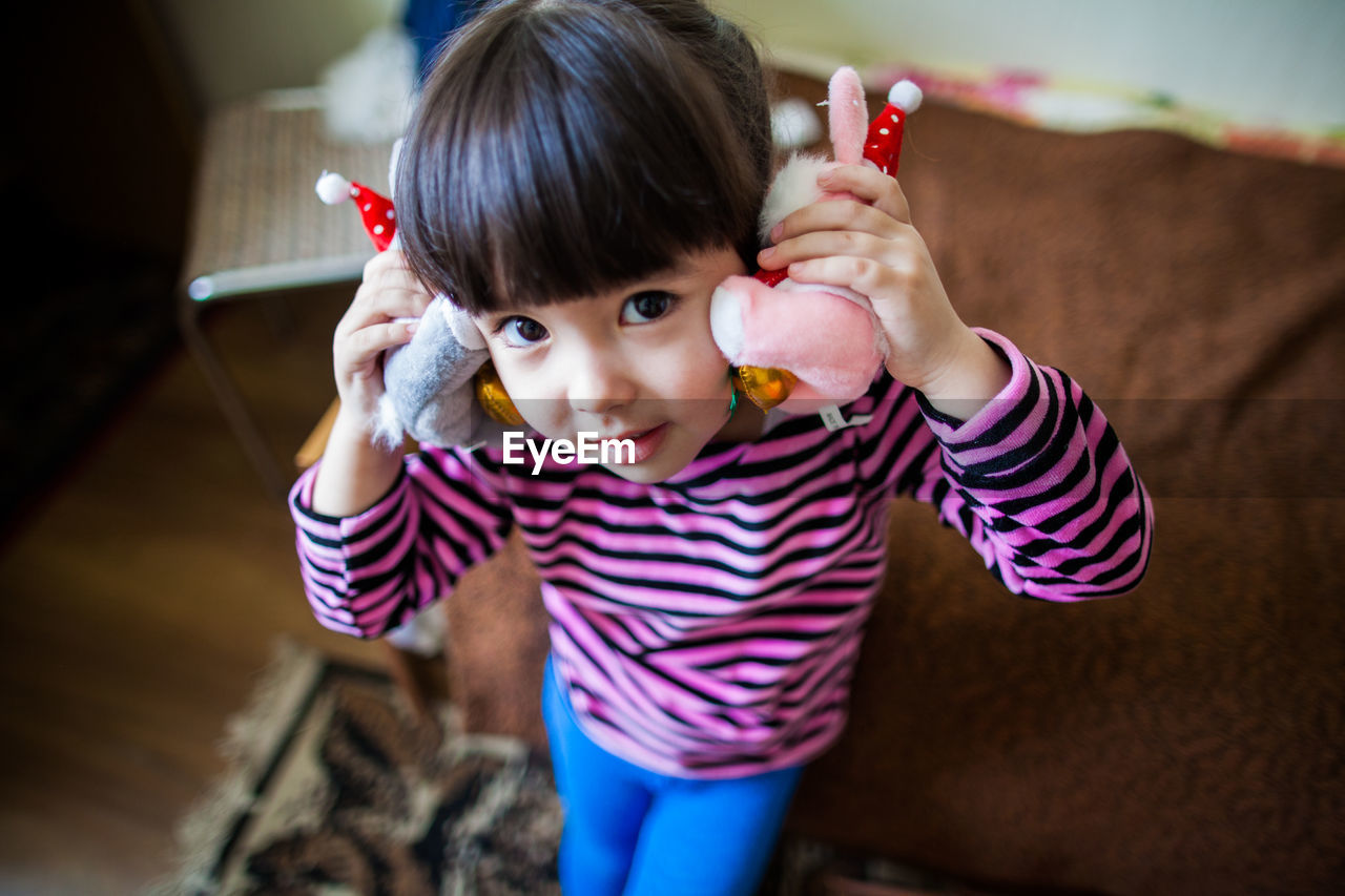 Portrait of cute girl holding toy at home