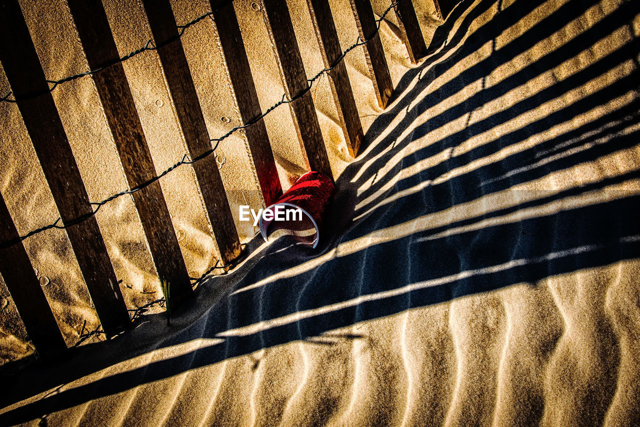 Shadow of fence on sand at beach