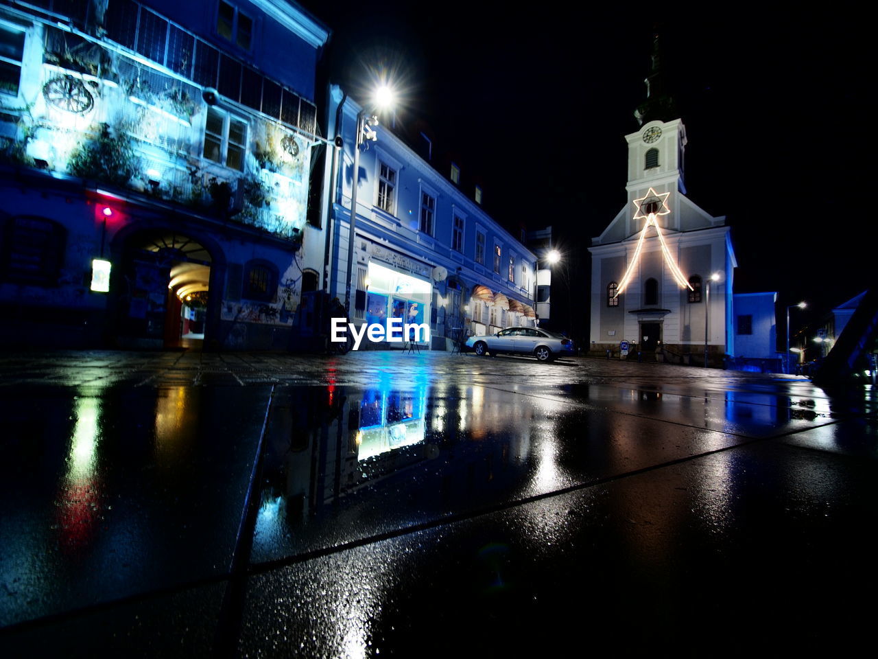 REFLECTION OF ILLUMINATED BUILDING IN PUDDLE