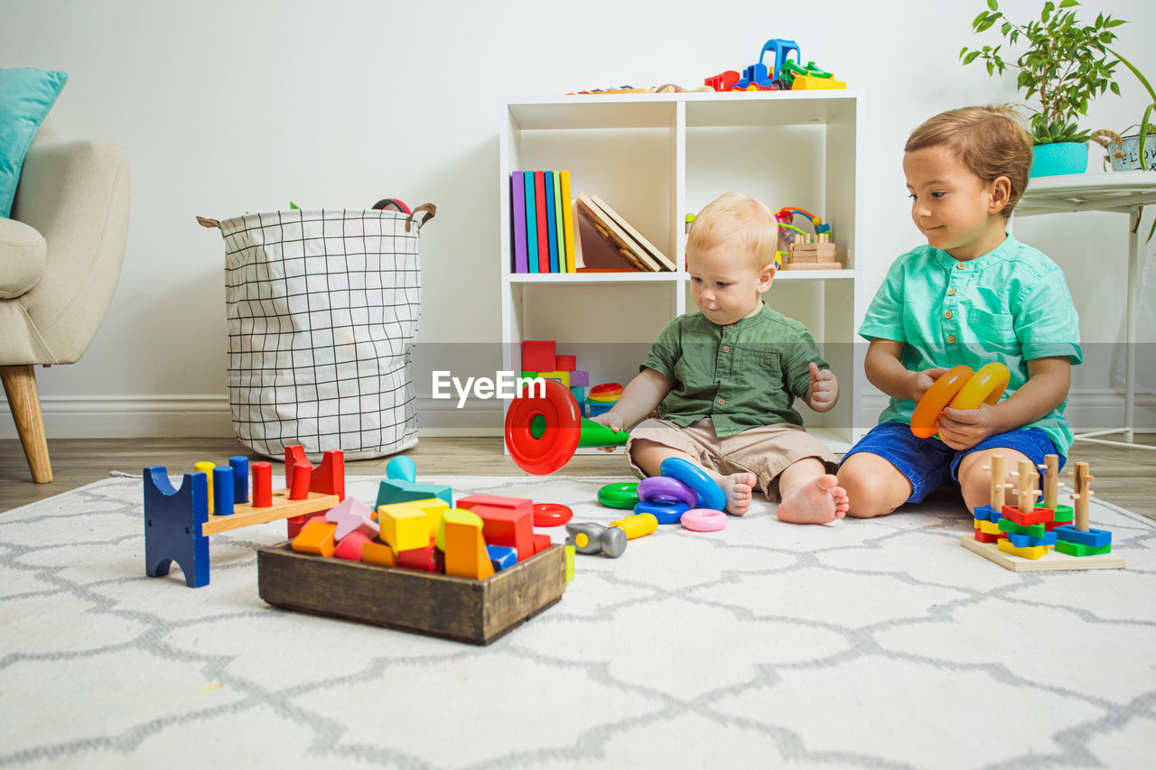 Boy playing with toy sitting on floor at home