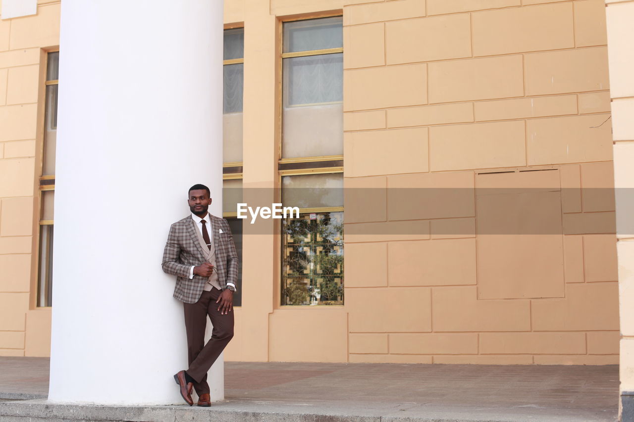 Man in suit standing against building