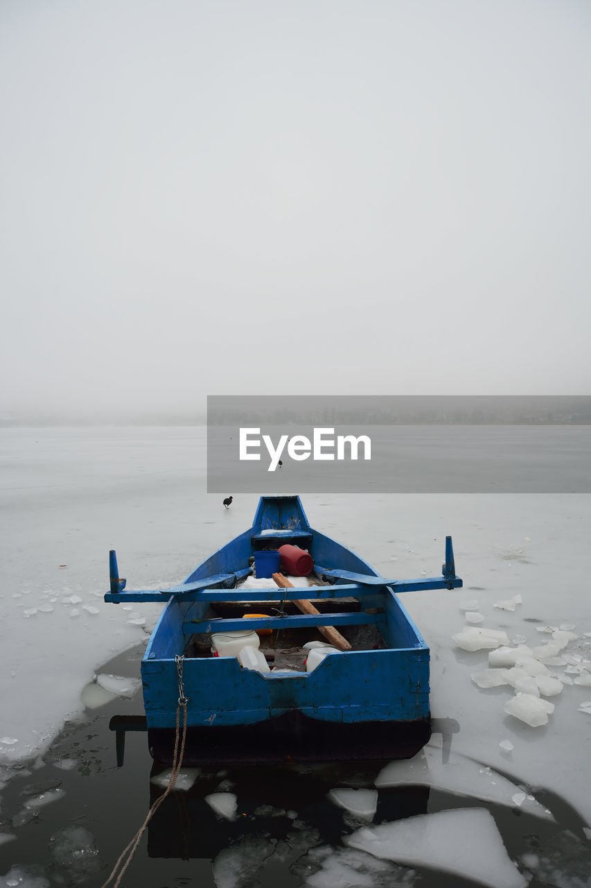 BOAT MOORED ON SEA AGAINST SKY