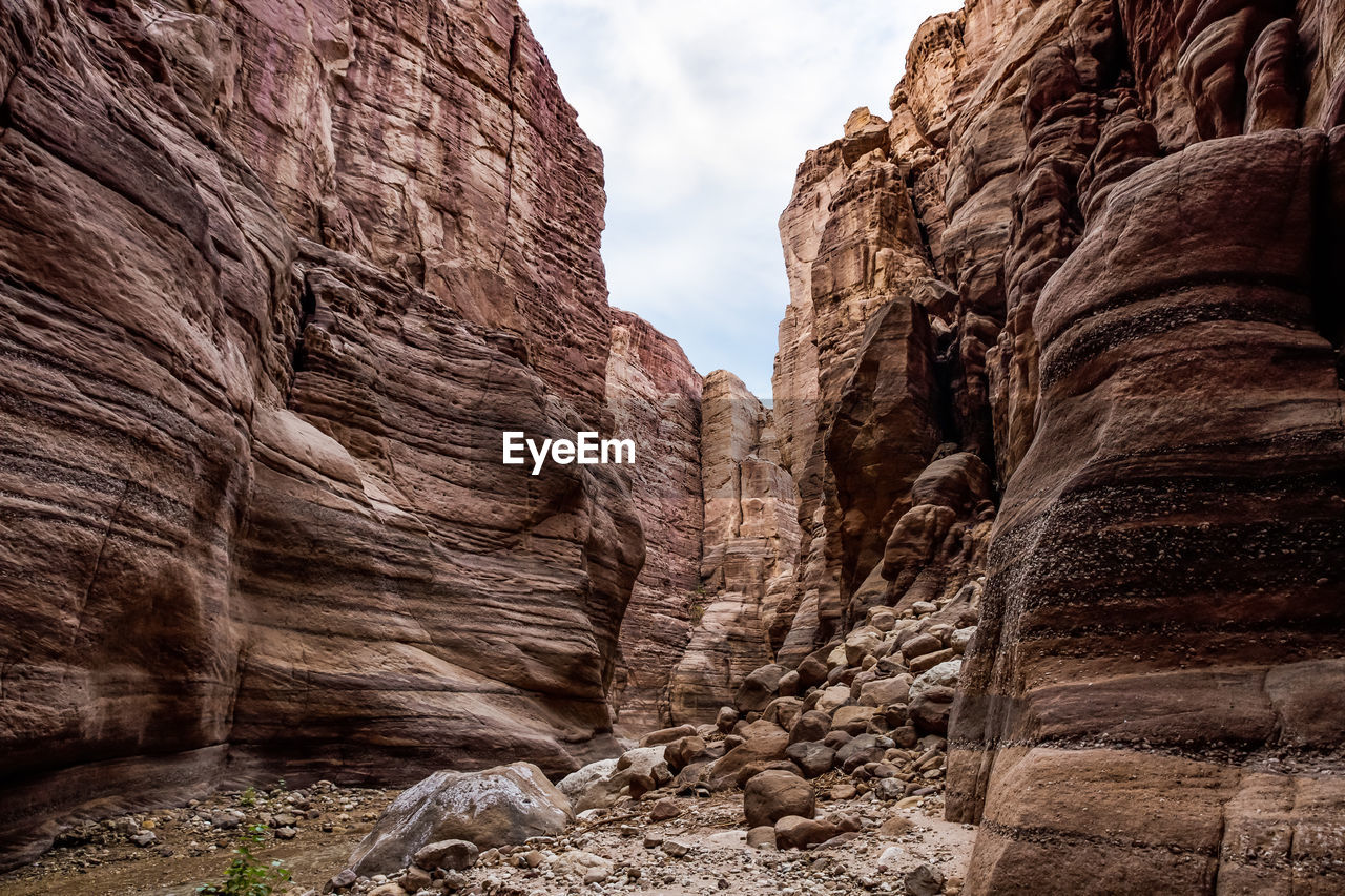 rock, rock formation, arch, nature, travel destinations, canyon, scenics - nature, wadi, beauty in nature, landscape, sky, environment, non-urban scene, travel, geology, land, no people, valley, cloud, cliff, eroded, sandstone, tranquility, outdoors, desert, physical geography, tourism, day, mountain, terrain, formation, extreme terrain, tranquil scene, architecture, plant, ancient history