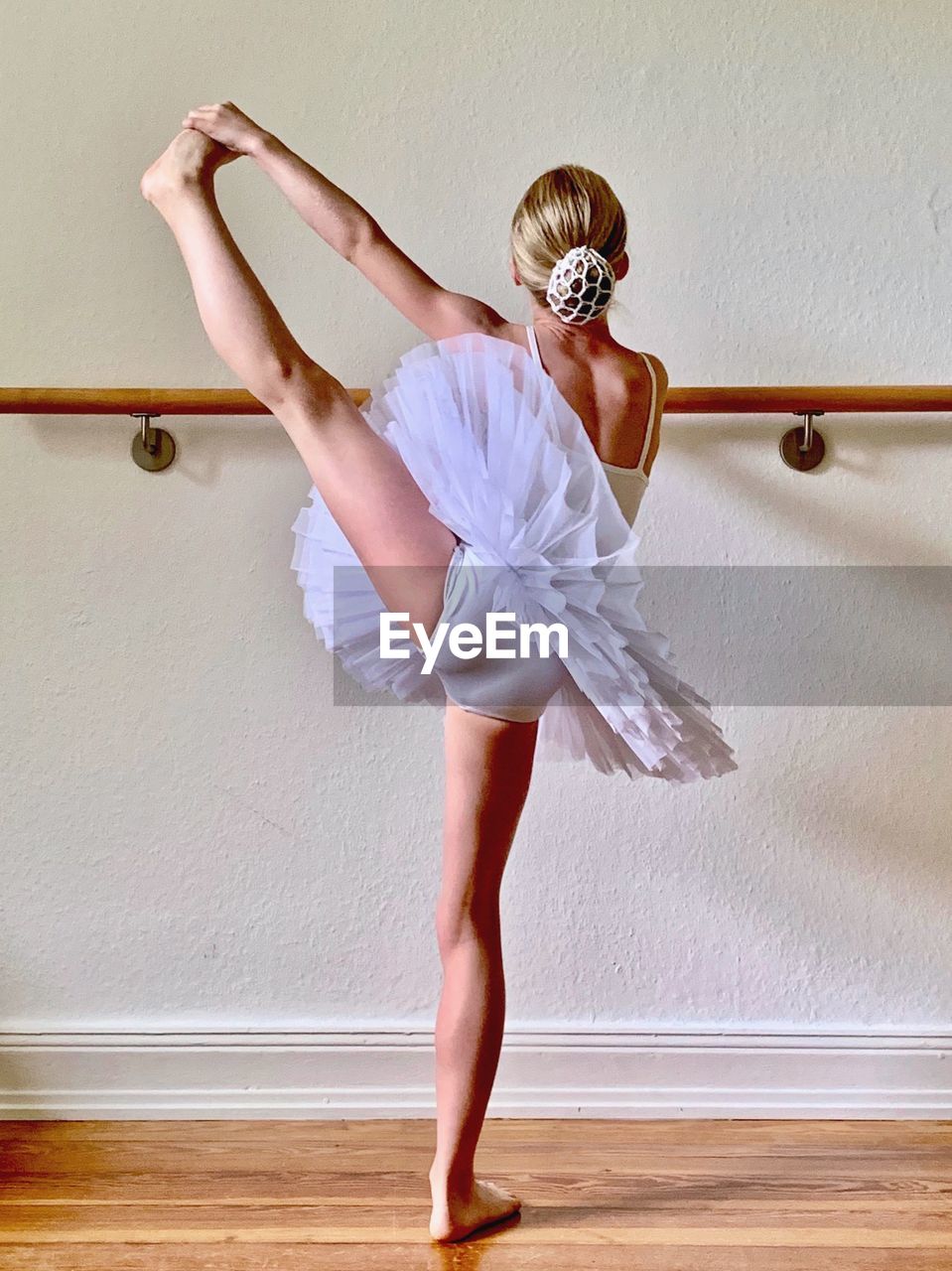 Rear view of girl stretching while practicing against wall