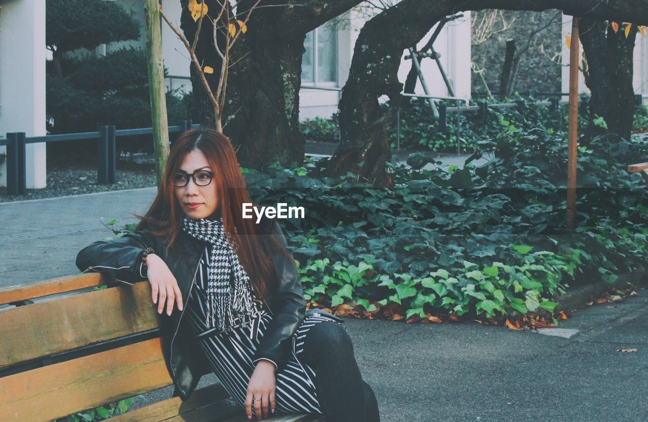 Thoughtful woman sitting on bench at sidewalk