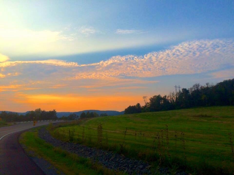 ROAD PASSING THROUGH FIELD AGAINST CLOUDY SKY AT SUNSET