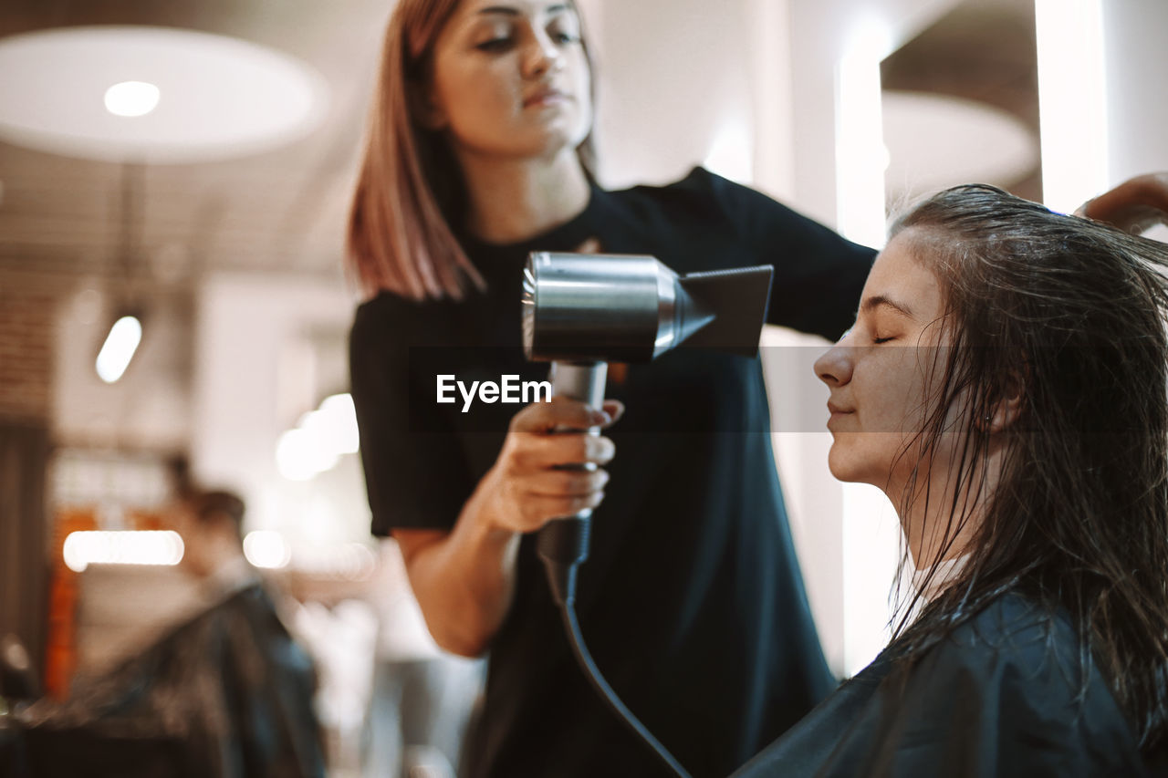 Hairdresser drying hair of customer at salon