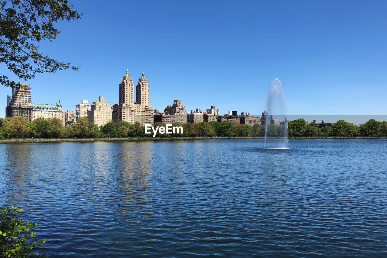 View of buildings by lake against sky